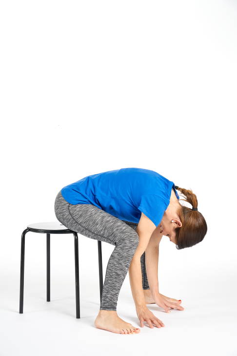 Ausgangsposition: Der Oberkörper ist zwischen den Beinen. Halten Sie die Position so lange Sie es als angenehm empfinden. © Gelenk-Klinik Sitz auf einem Stuhl. Der Oberkörper ist zwischen den Beinen.