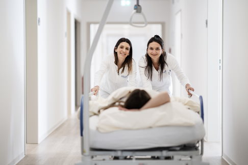 Unser engagiertes Pflegepersonal sorgt mit Kompetenz und Freundlichkeit für Ihr Wohlbefinden. © Gelenk-Klinik Krankenpflegerinnen schieben ein Bett