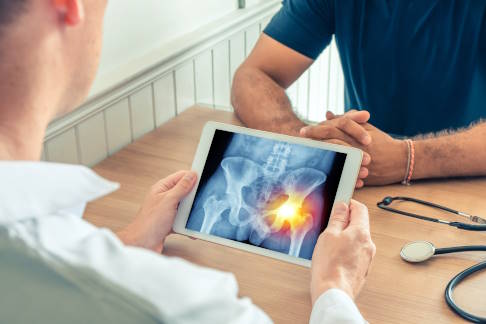 Die Bildgebung ist ein essenzieller Baustein moderner Diagnostik. © steph photographies, Adobe Orthopäde erklärt Patient ein Röntgenbild.