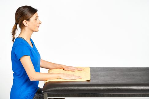 Legen Sie die Hände auf einem Handtuch ab. © Gelenk-Klinik Am Tisch sitzend, Ausgangsstellung