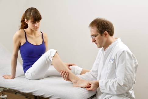 Klinische Untersuchung des Morton Neuroms zwischen den Zehenstrahlen des Mittelfußes (Metatarsalknochen) durch das Mulder-Zeichen: Der Fußspezialist kann das Morton Neurom zwischen den Mittelfußknochen ertasten und einen spezifischen Druckschmerz auslösen. © Gelenk-Klinik Arzt untersucht Fuß
