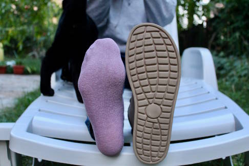 Wer unter einem Morbus Ledderhose leidet, sollte auf gut passendes, ausreichend weites und weiches Schuhwerk achten. © Adobe, Anna Frau vergleicht ihre Füße. Der eine Fuß trägt einen Schuh, der andere eine Socke.