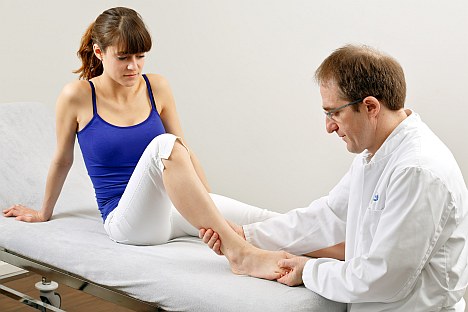 Im Anfangsstadium ist der Hallux valgus für viele lediglich ein kosmetisches Problem. Wir empfehlen aber eine frühzeitige Korrektur der Großzehenstellung durch Fußgymnastik, Hallux valgus-Schienen oder operative Stellungskorrektur, bevor bleibende Schäden auftreten. © Gelenk-Klinik Arzt untersucht Patientin