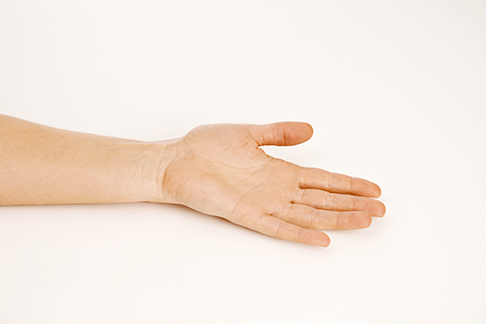 Die Hand liegt mit dem Handrücken locker auf dem Tisch. © Gelenk-Klinik Ausgangsposition