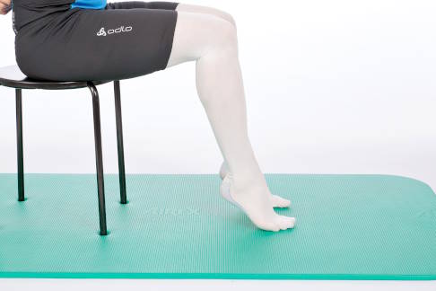 Rollen Sie die Füße auf die Fußspitze. © Gelenk-Klinik Sitz auf Stuhl, die Füße auf der Fußspitze.