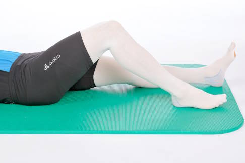 Übung in Rückenlage, ein Bein ist aufgestellt. © Gelenk-Klinik Rückenlage auf Matte, ein Bein aufgestellt