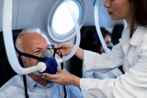 In einer Überdruckkammer atmet der Patient reinen Sauerstoff über eine Maske. © Drazen, Adobe Mann mit O2-Maske in Überdruckkammer
