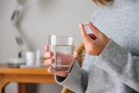 Frau mit Tablette und Wasserglas