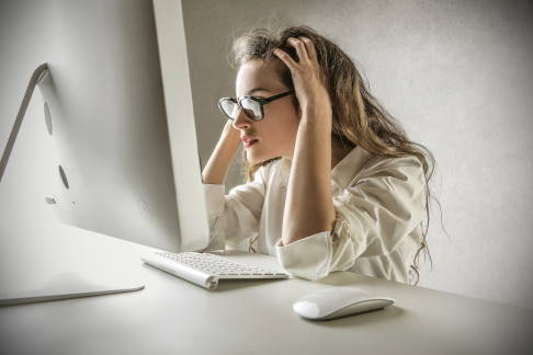 Unter Zeitdruck und Anspannung erledigen wir viele Dinge gleichzeitig. Dieses angespannte Arbeiten vor dem Computer begünstigt die Entstehung eines Mausarms. © olly, Adobe Stock Frau am Computer mit Mausarm