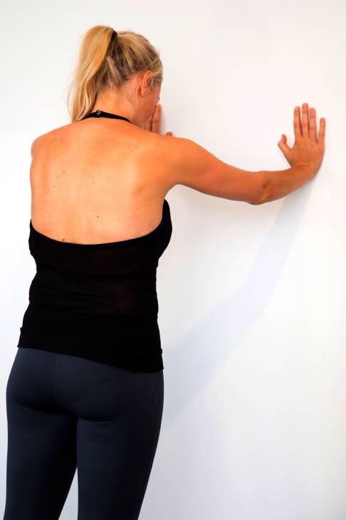 Drücken Sie Ihren Brustkorb von den Händen weg. Die Schulterblätter bewegen sich auseinander. © Gelenk-Klinik Brustkorb von der Wand wegbewegen
