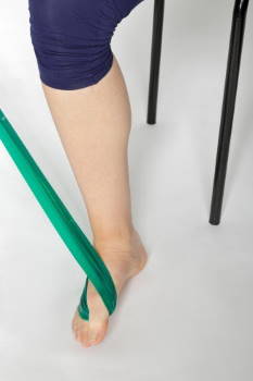 Fuß gegen den Widerstand des Bandes zum Boden drücken. © Gelenk-Klinik Fuß gegen den Widerstand des Bandes zum Boden drücken